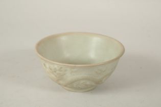 A CHINESE CELADON BOWL, with relief dragon and phoenix. 13cms diameter.