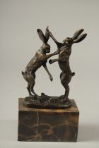 A PAIR OF BRONZE FIGHTING HARES. Signed. 17cms high on a marble base.