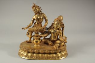 A GOOD GILT BRONZE DOUBLE GOD FIGURE, one playing a drum, set with stones. 27cms high x 27cms long.