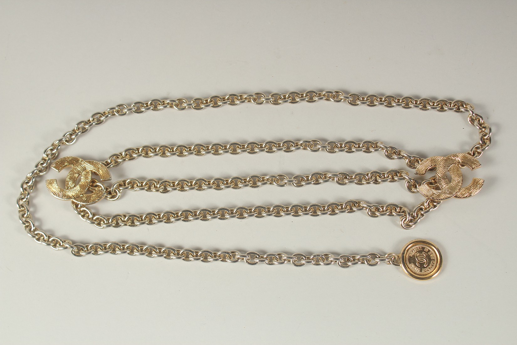 A LONG CHANEL GILT BELT with pendant and tie, double C emblem. 110cms long.