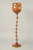 A 1970'S TURNED WOOD GOBLET on a circular base. 29ins high.