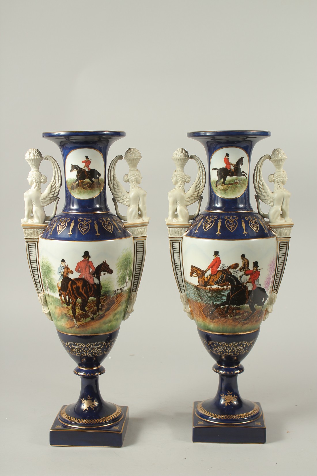 A PAIR OF SEVRES DESIGN BLUE GROUND TWO HANDLED HUNTING VASES. 46cms high.