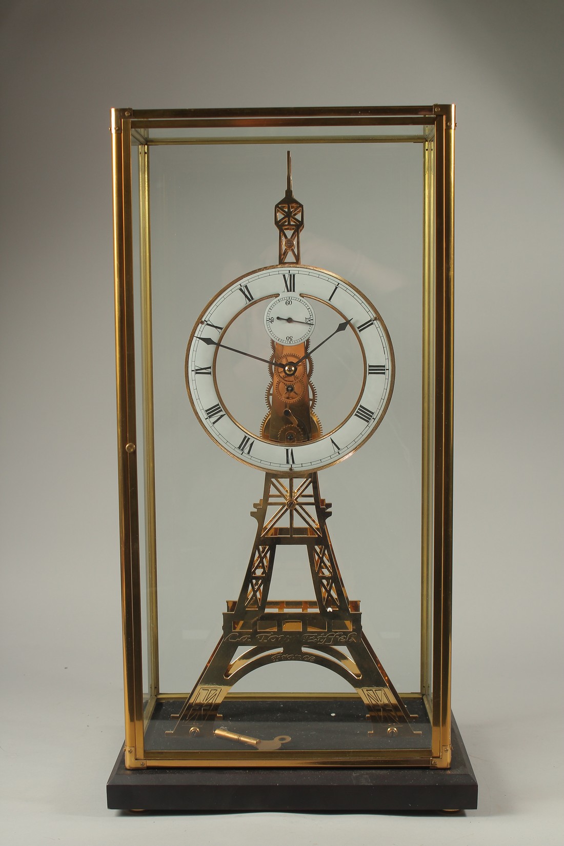 AN EIFFEL TOWER BRASS SKELETON CLOCK in a glass case. 56cms high.