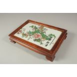 A CHINESE PORCELAIN AND HARDWOOD STAND with calligraphy and flowers. 27 x 18cms.