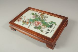 A CHINESE PORCELAIN AND HARDWOOD STAND with calligraphy and flowers. 27 x 18cms.