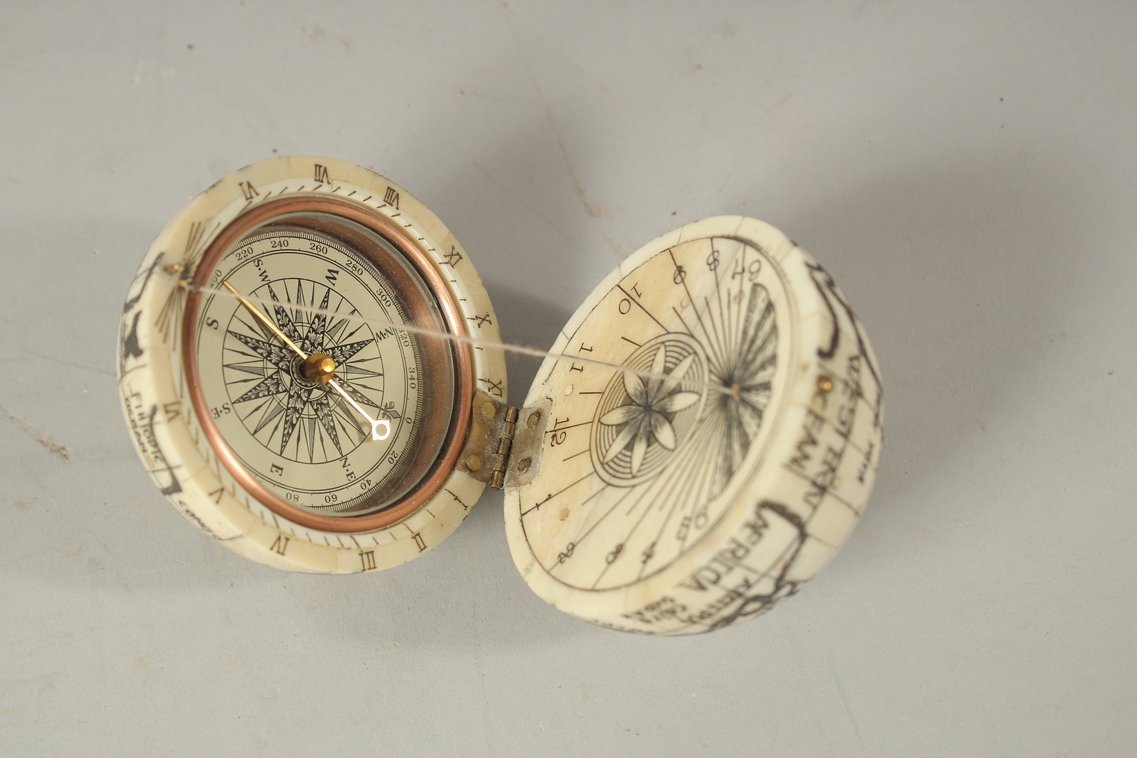 AN ETCHED BONE COMPASS. 6cms diameter.