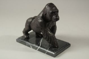 A BRONZE GORILLA on a marble base. 16cms long.