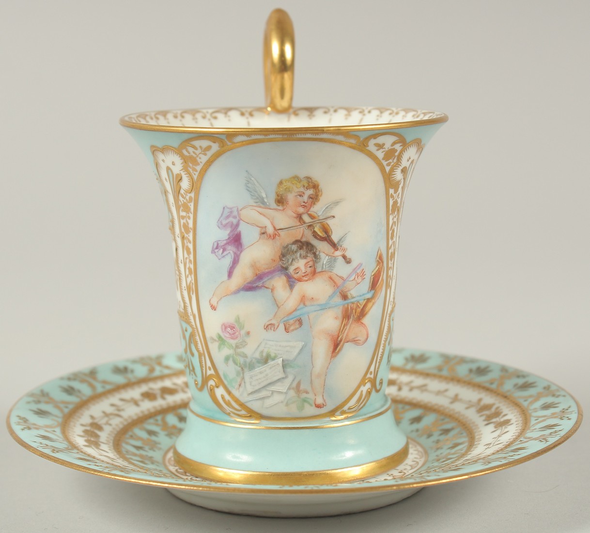 A GOOD DRESDEN CUP AND SAUCER with blue ground, painted with an oval of a two cupids playing