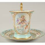 A GOOD DRESDEN CUP AND SAUCER with blue ground, painted with an oval of a two cupids playing