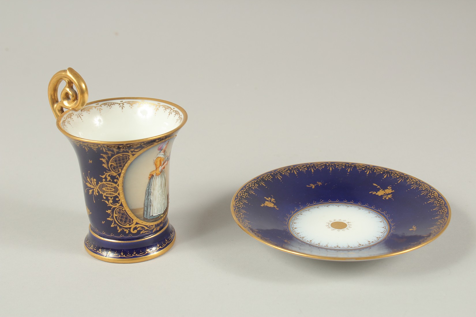 A GOOD DRESDEN CUP AND SAUCER with blue ground, painted with an oval of a lady carrying a tray. - Image 2 of 9
