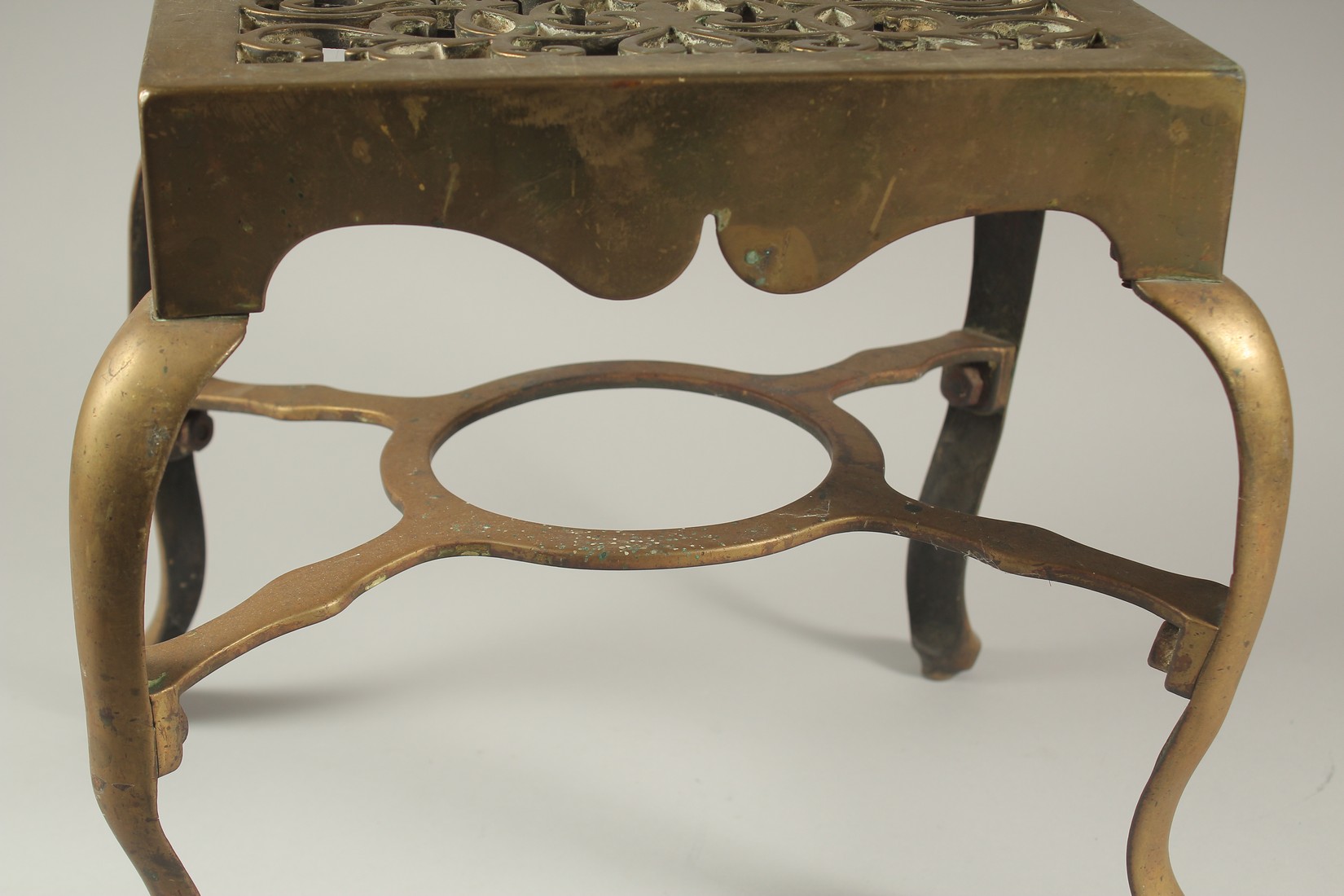 A LARGE BRASS TRIVET with pierced top and four curving legs. 1ft wide x 4ft high. - Image 3 of 3