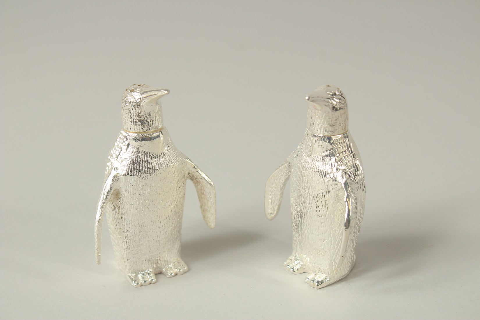 A SMALL PAIR OF PLATED PENGUIN SALTS AND PEPPERS. 3cms high.