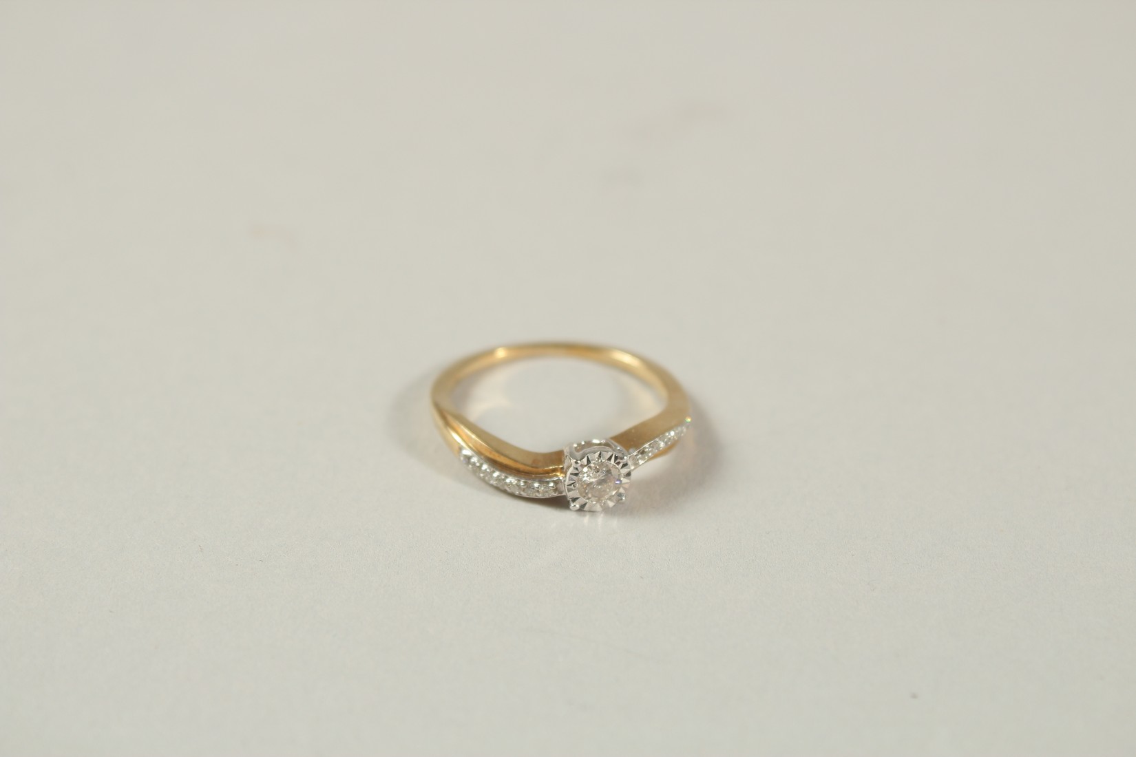 A 9CT YELLOW GOLD SOLITAIRE-STYLE RING SET WITH 0.22 RBC DIAMONDS IN TOTAL, in a twist-style - Image 2 of 5