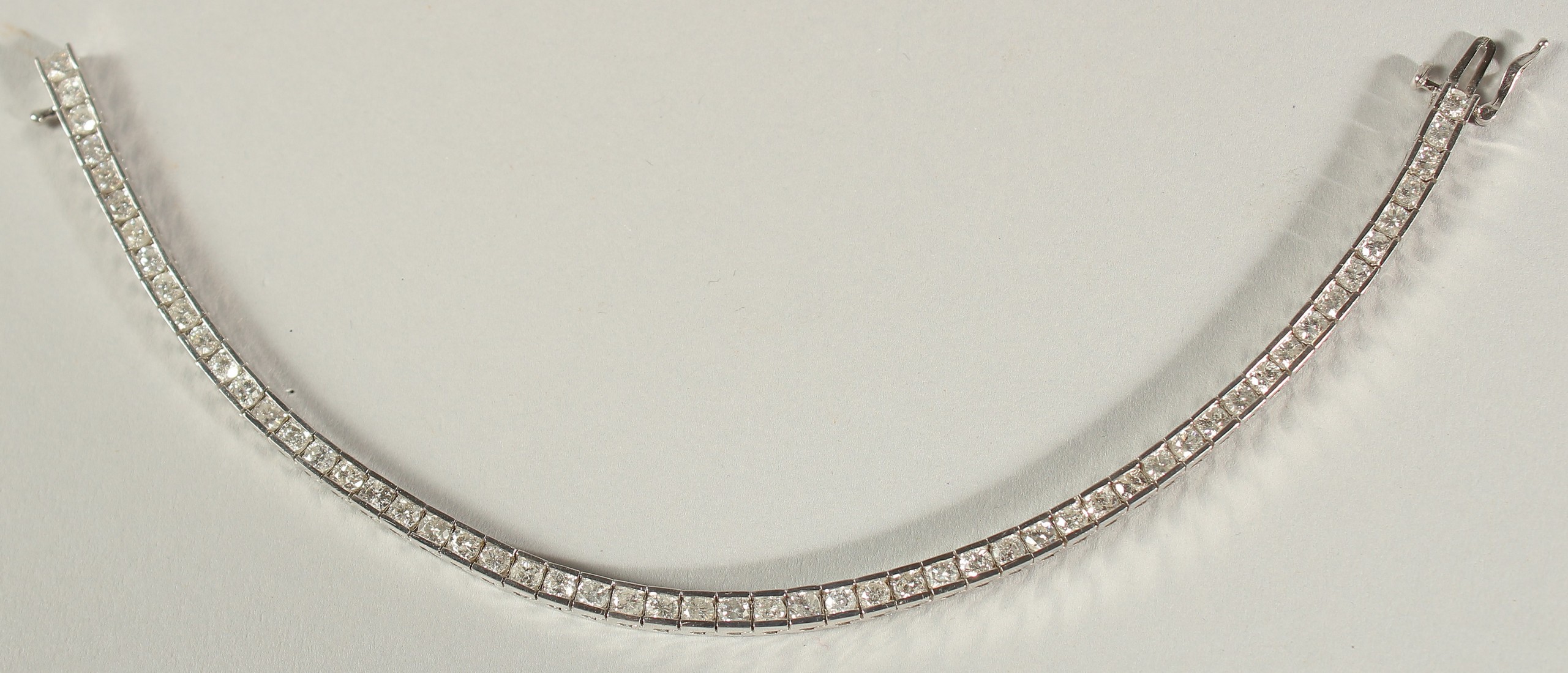 A 14CT WHITE GOLD SEMI-RUBOVER SET RBC DIAMOND LINE BRACELET, with an open blox clasp and safety