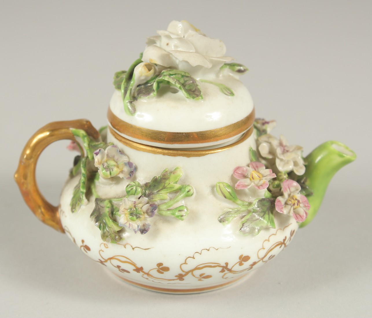 A GOOD SMALL ROCKINGHAM TEAPOT encrusted with flowers. Rockingham mark in puce. 3.5ins diameter.
