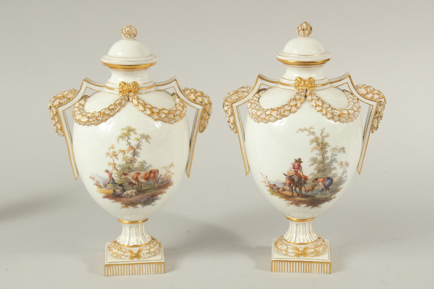 A PAIR OF MEISSEN LIDDED VASES painted with figures in pastoral landscapes. The body of the vases