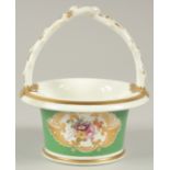 A GOOD SMALL ROCKINGHAM CIRCULAR BASKET and handle, green ground and painted with flowers.