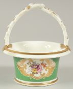 A GOOD SMALL ROCKINGHAM CIRCULAR BASKET and handle, green ground and painted with flowers.