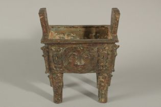 A BRONZE TWIN HANDLE RECTANGULAR CENSER, elevated on four legs, with four archaic-style faces,
