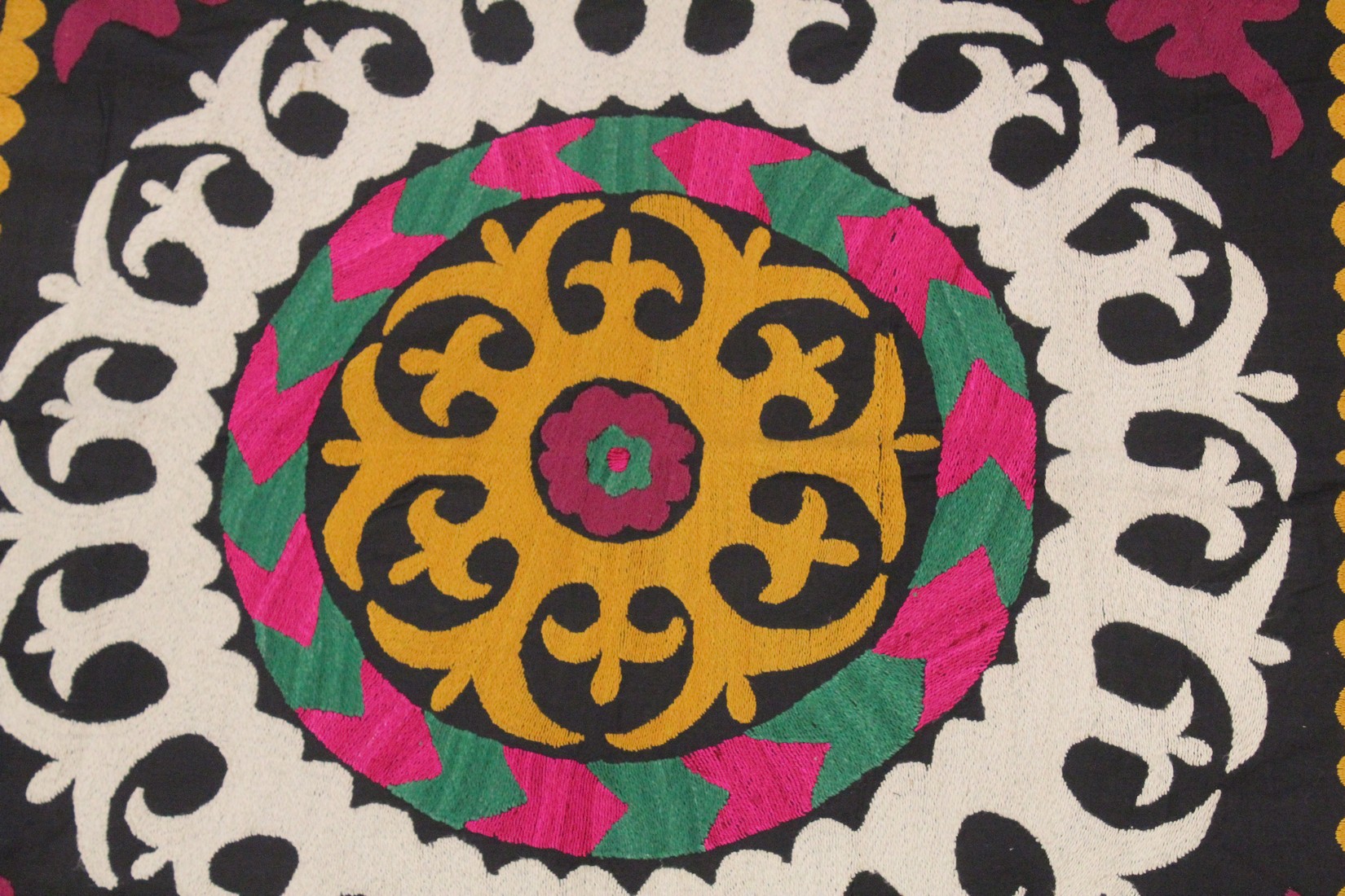 AN UZBEK SUZANI EMBROIDERED TEXTILE, with central foliate motif in yellow, green, maroon, black, and - Image 2 of 3