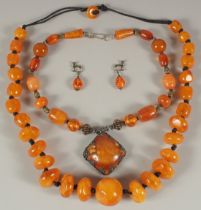 TWO AMBER RESIN BERBER NECKLACES AND A PAIR OF EARRINGS.