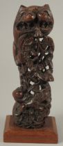 A CARVED AND PIERCED WOOD ORNAMENTAL FIGURE, mounted to a wooden base, 24.5cm high.