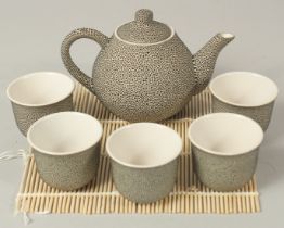 A JAPANESE SPECKLE-GLAZED CERAMIC TEA SET; comprising a teapot and five cups, (6).