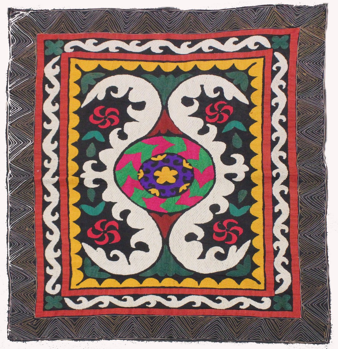 AN UZBEK SUZANI EMBROIDERED TEXTILE, with central foliate motif in purple, yellow, green, red,