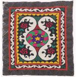 AN UZBEK SUZANI EMBROIDERED TEXTILE, with central foliate motif in purple, yellow, green, red,