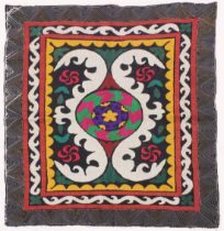 AN UZBEK SUZANI EMBROIDERED TEXTILE, with central foliate motif in purple, yellow, green, red,