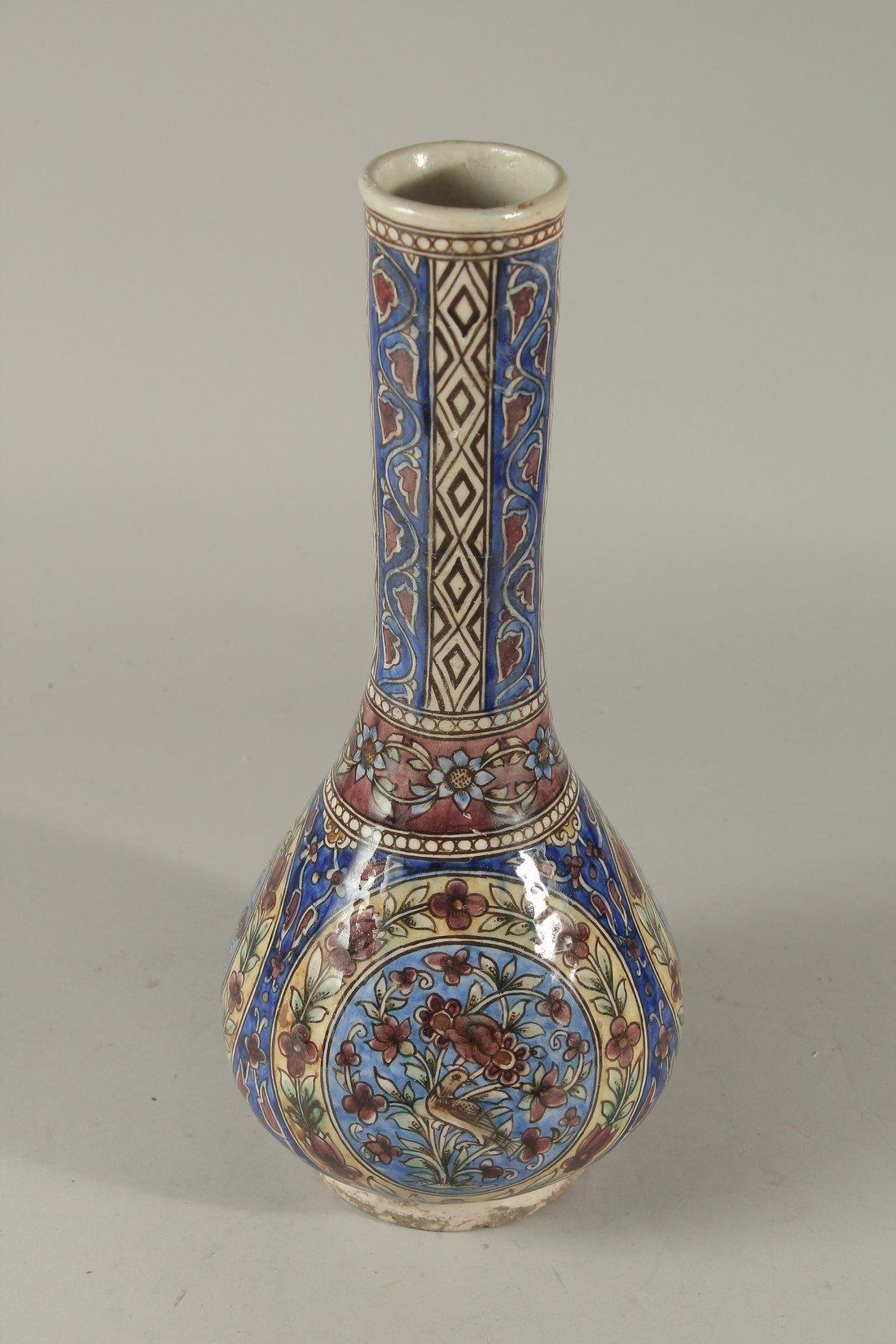 A PERSIAN QAJAR GLAZED POTTERY VASE, painted with panels depicting a bird amongst flora, further