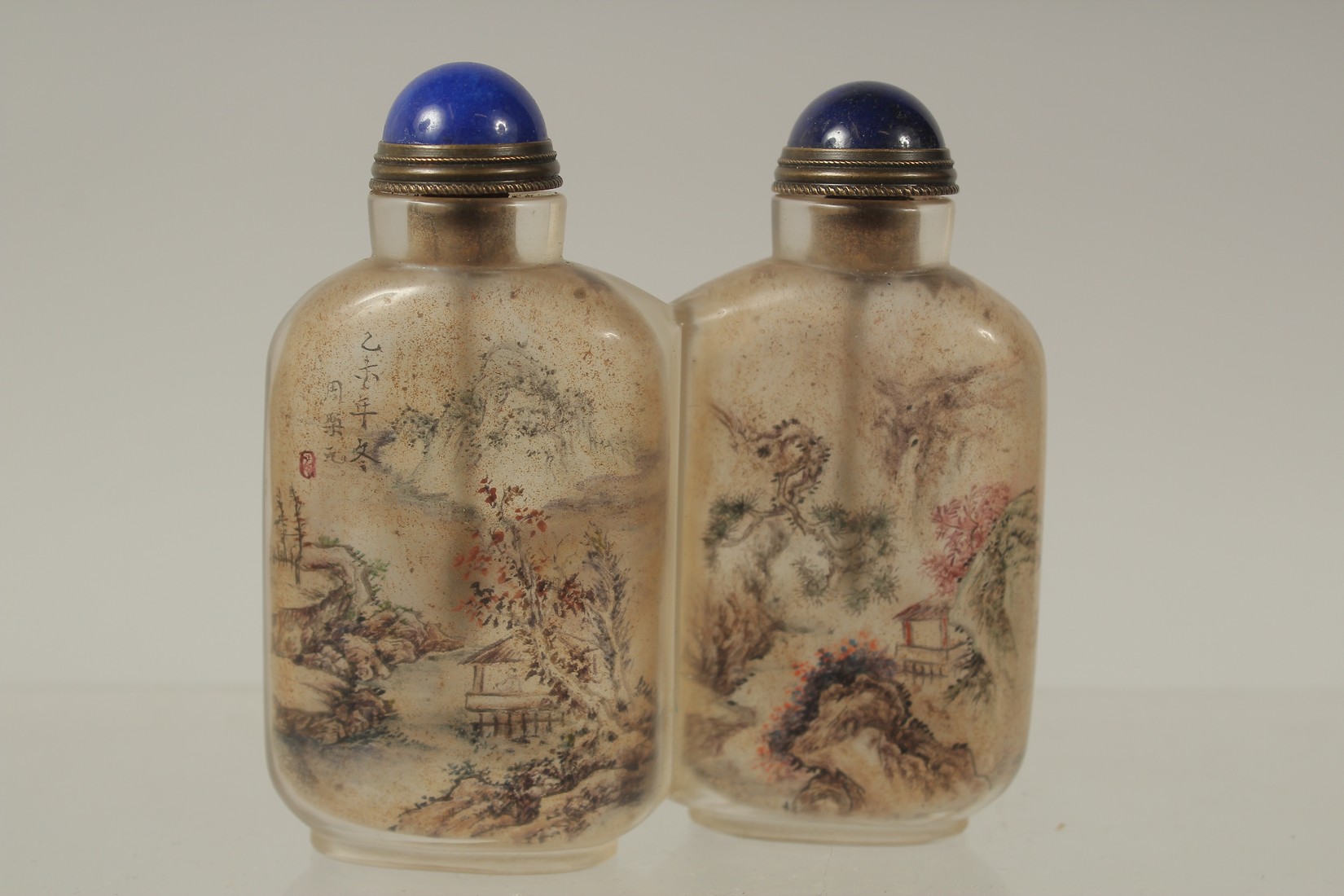 A CHINESE REVERSE GLASS PAINTED DOUBLE-SNUFF BOTTLE AND STOPPERS, finely painted with a landscape