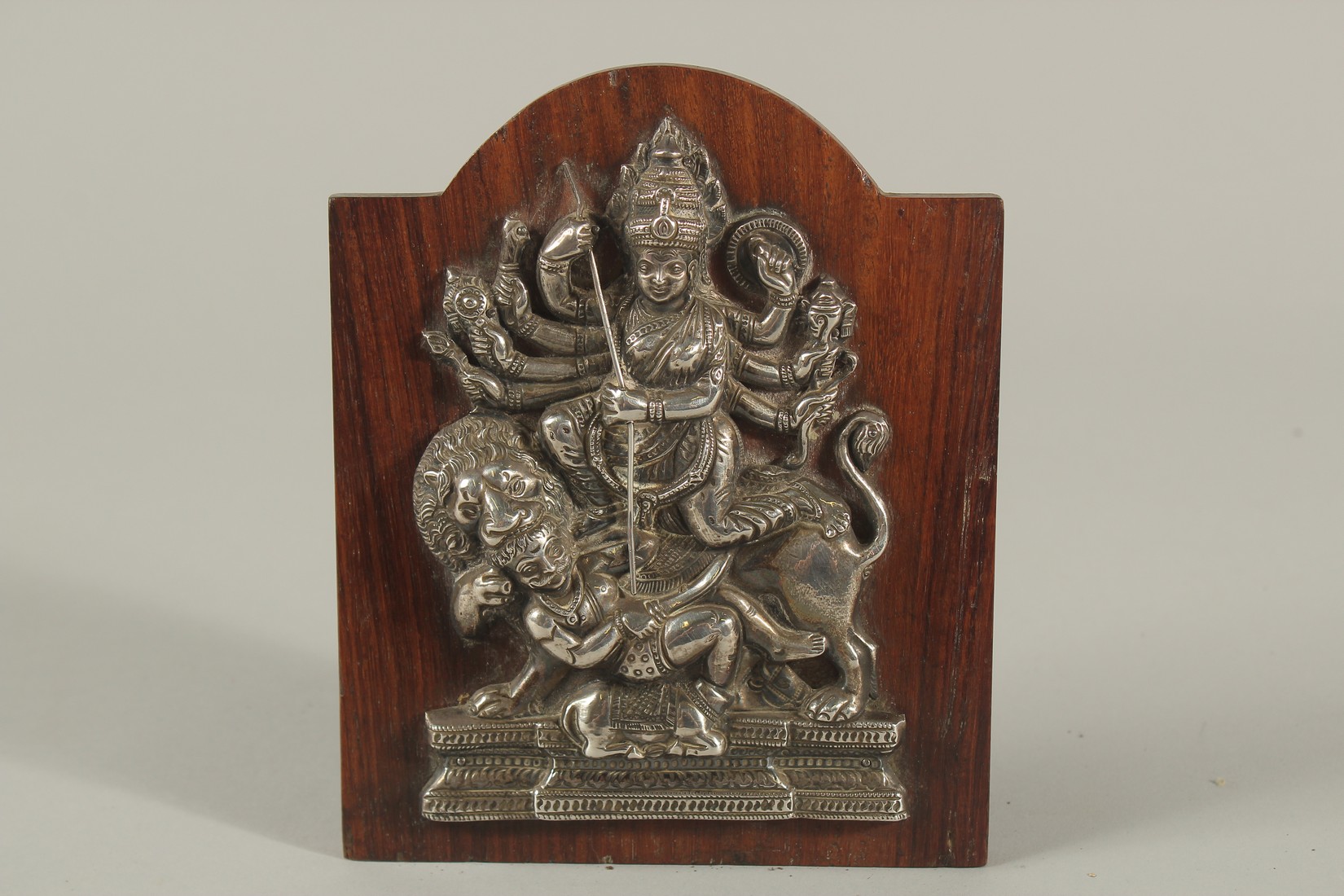 A FINE SOUTH INDIAN SILVER HINDU DEITY MOUNTED TO A WOODEN PLAQUE, 16cm high.