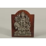 A FINE SOUTH INDIAN SILVER HINDU DEITY MOUNTED TO A WOODEN PLAQUE, 16cm high.