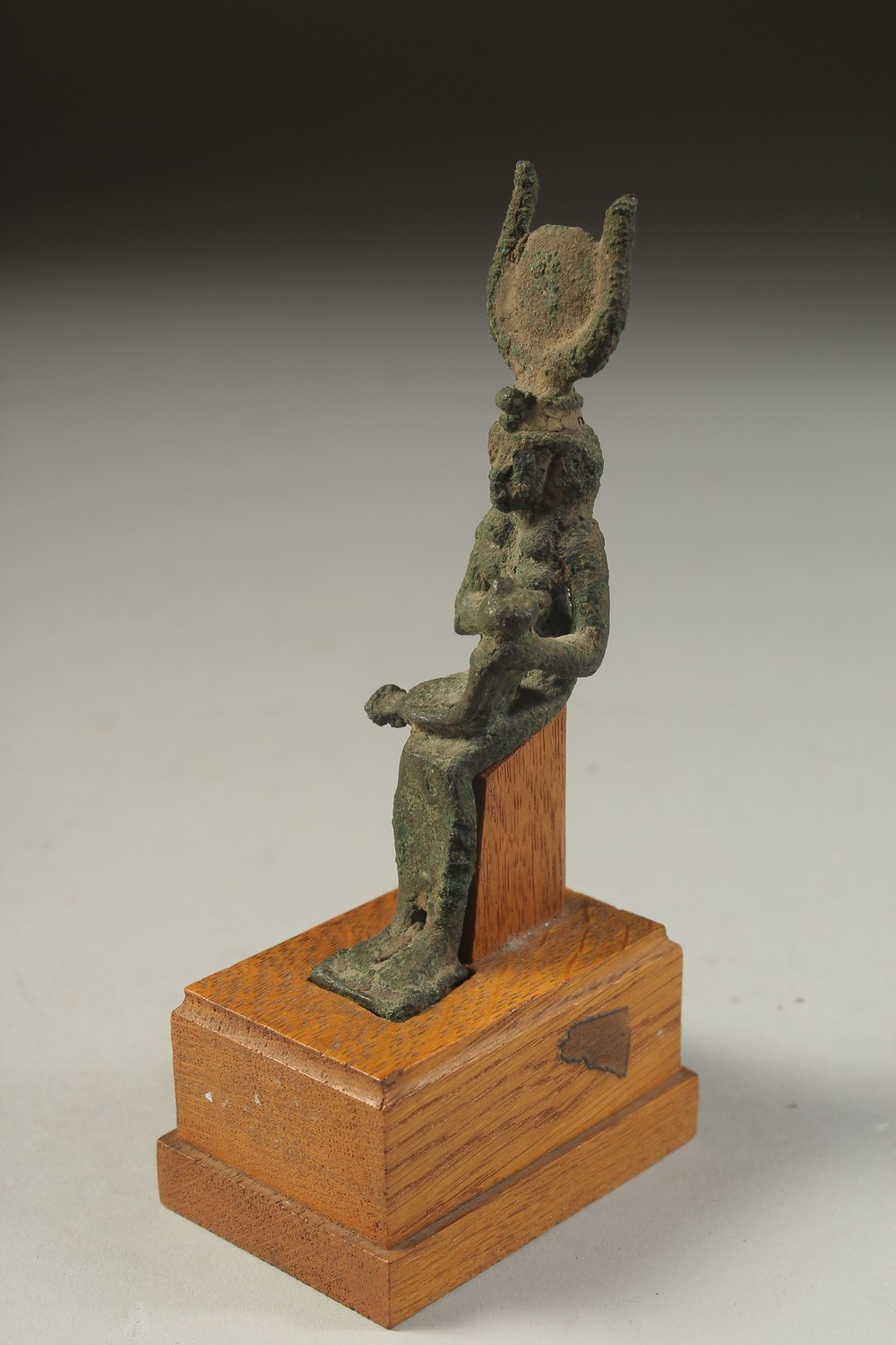A RARE ANCIENT EYGPTIAN BRONZE FIGURE OF ISIS NURTURING HORUS, on a wooden stand, bronze 12cm high.