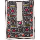 AN UZBEK SUZANI EMBROIDERED TEXTILE, with floral motifs and decorative roundels in pink, red, green,