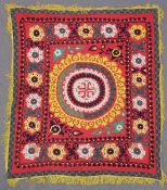 AN UZBEK SUZANI EMBROIDERED TEXTILE, with floral motifs in yellows, greens, purple, black, and