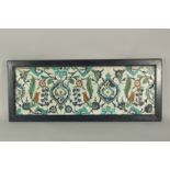 THREE ISLAMIC GLAZED POTTERY FLORAL TILES UNITED IN A WOODEN FRAME, 33cm x 82cm overall.