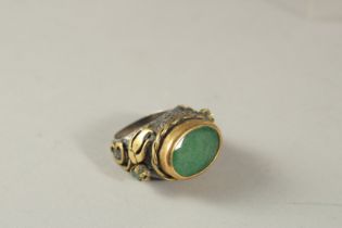 AN OVAL GREEN-STONE INSET MIXED METAL RING.
