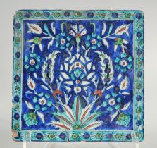 AN IZNIK BLUE AND TURQUOISE GLAZED POTTERY TILE, painted with foliate motifs, 20cm square.