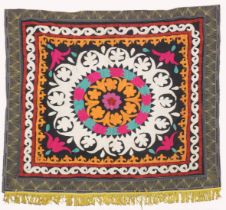 AN UZBEK SUZANI EMBROIDERED TEXTILE, with central foliate motif in orange, pink, red, green,