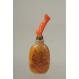 A CHINESE AGATE SNUFF BOTTLE WITH CORAL STOPPER, the bottle carved with carp, 11.5cm high overall.