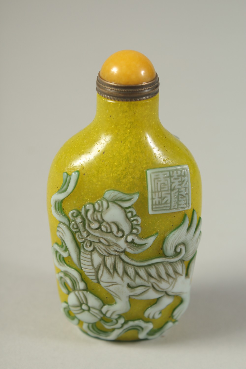 A CHINESE RELIEF-DECORATED FOO DOG SNUFF BOTTLE AND STOPPER / SPOON, 8cm high. - Image 2 of 4