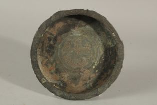 A 13TH CENTURY PERSIAN SELJUK BRONZE DISH, the centre depicting a mythical creature, 15cm diameter.