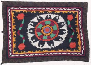 AN UZBEK SUZANI EMBROIDERED TEXTILE, with central foliate motif in orange, mauve, red, maroon,
