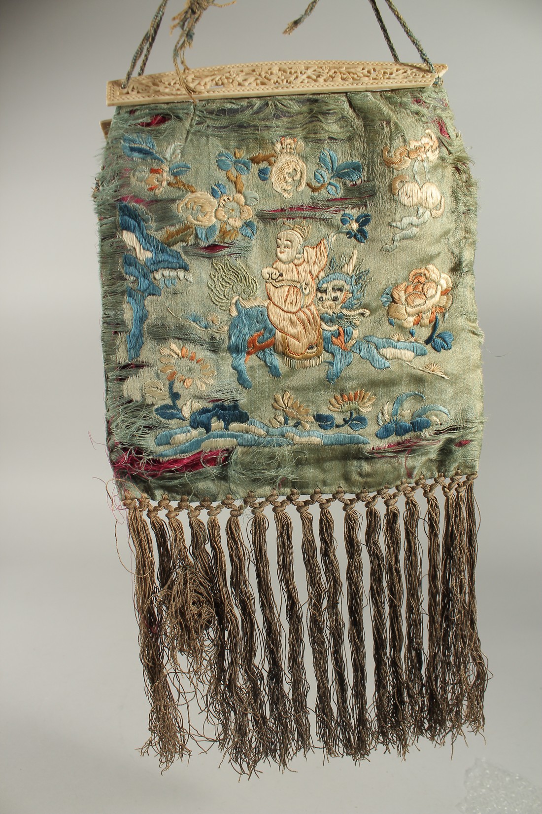 A CHINESE EMBROIDERED SILK PURSE WITH PIERCED BONE HANDLES.