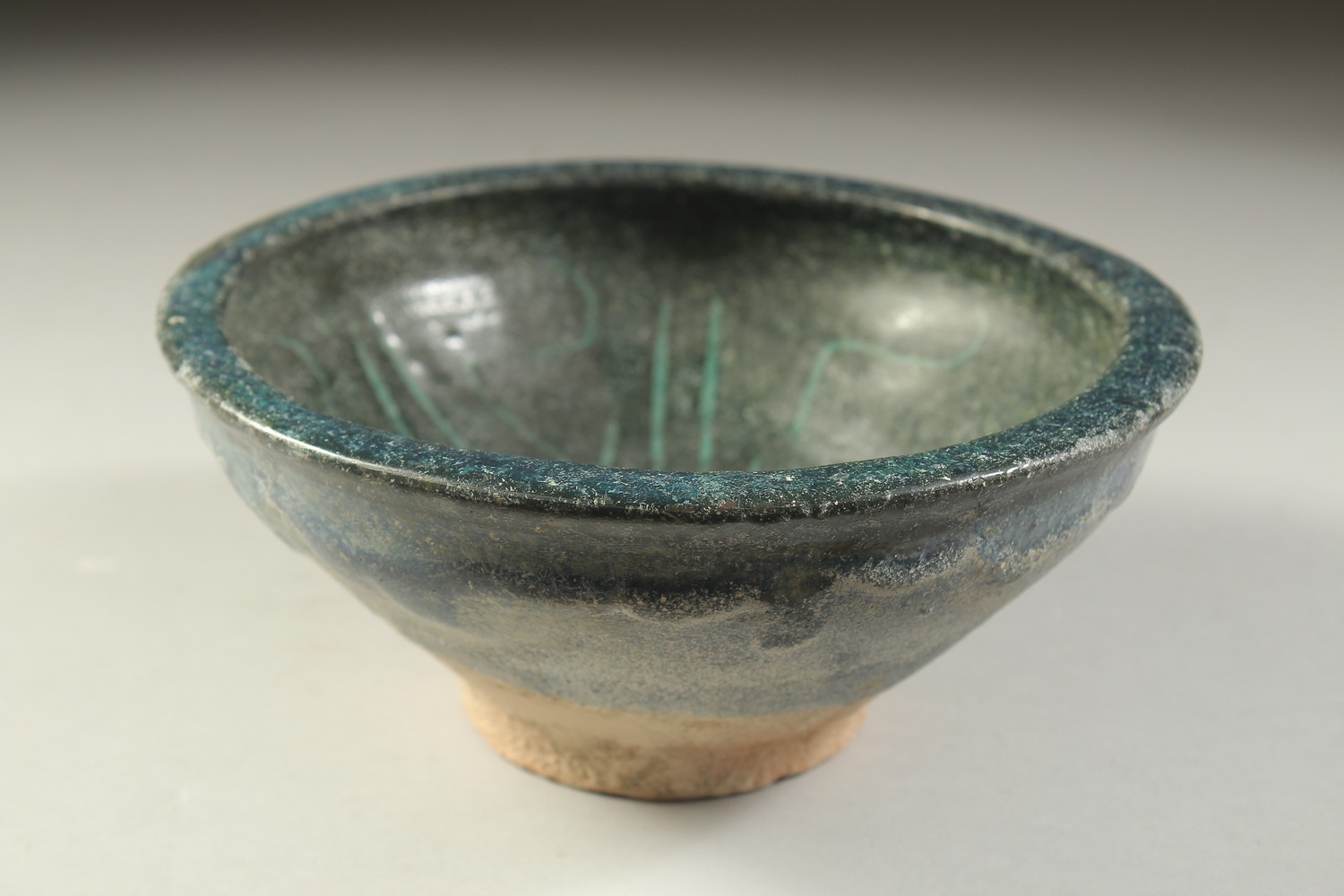 A 12TH CENTURY NISHAPUR GLAZED POTTERY BOWL, the interior with calligraphy, 19cm diameter.