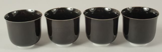 A SET OF FOUR BLACK GLAZE SAKE CUPS, 8cm high, 9cm diameter, in original fitted box.