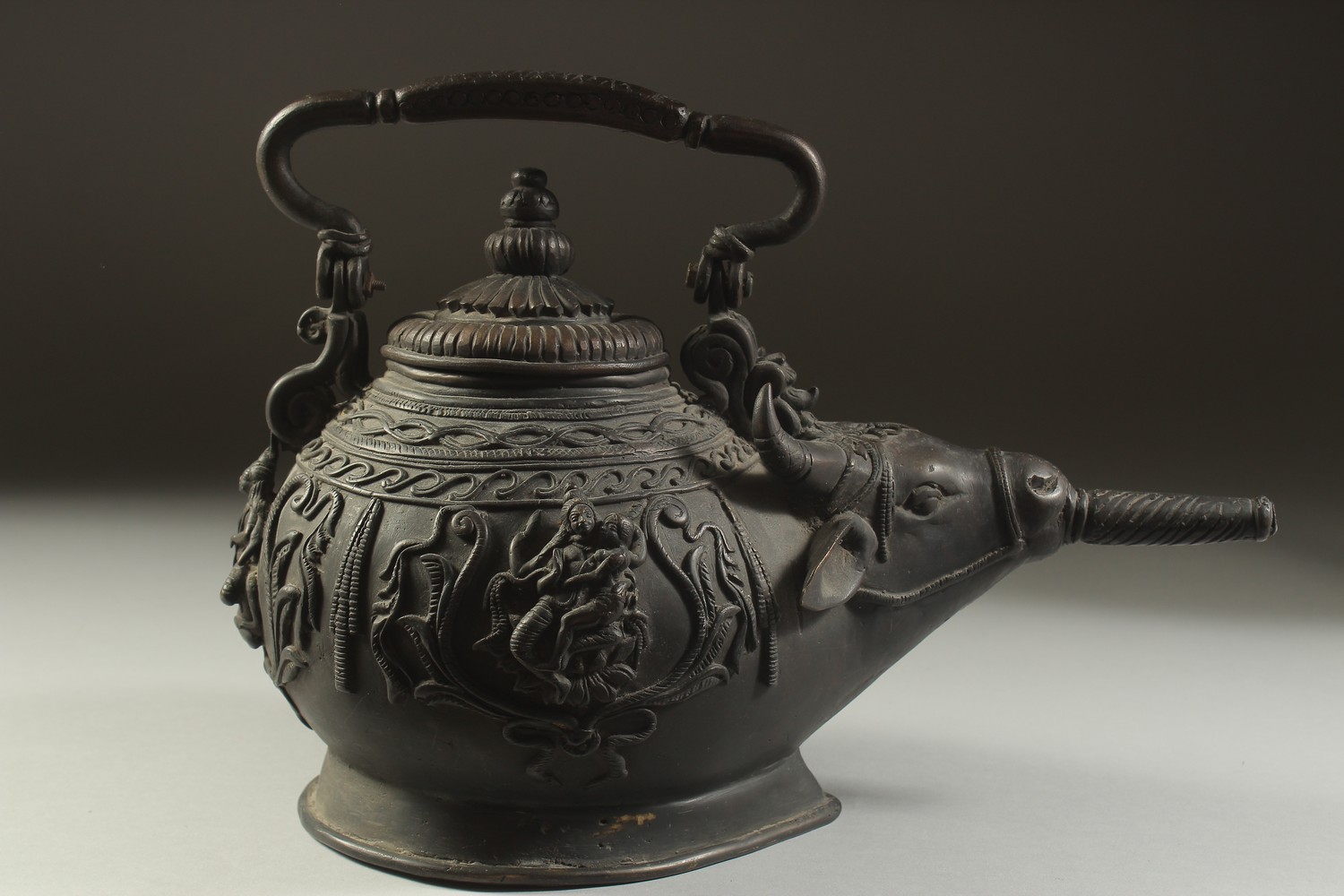 A FINE AND UNUSUAL INDIAN BRONZE EWER, with bulls' head spout and relief hindu deities around the