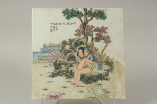 A CHINESE EROTIC POLYCHROME PORCELAIN PLAQUE, depicting two lovers beneath a tree and calligraphy